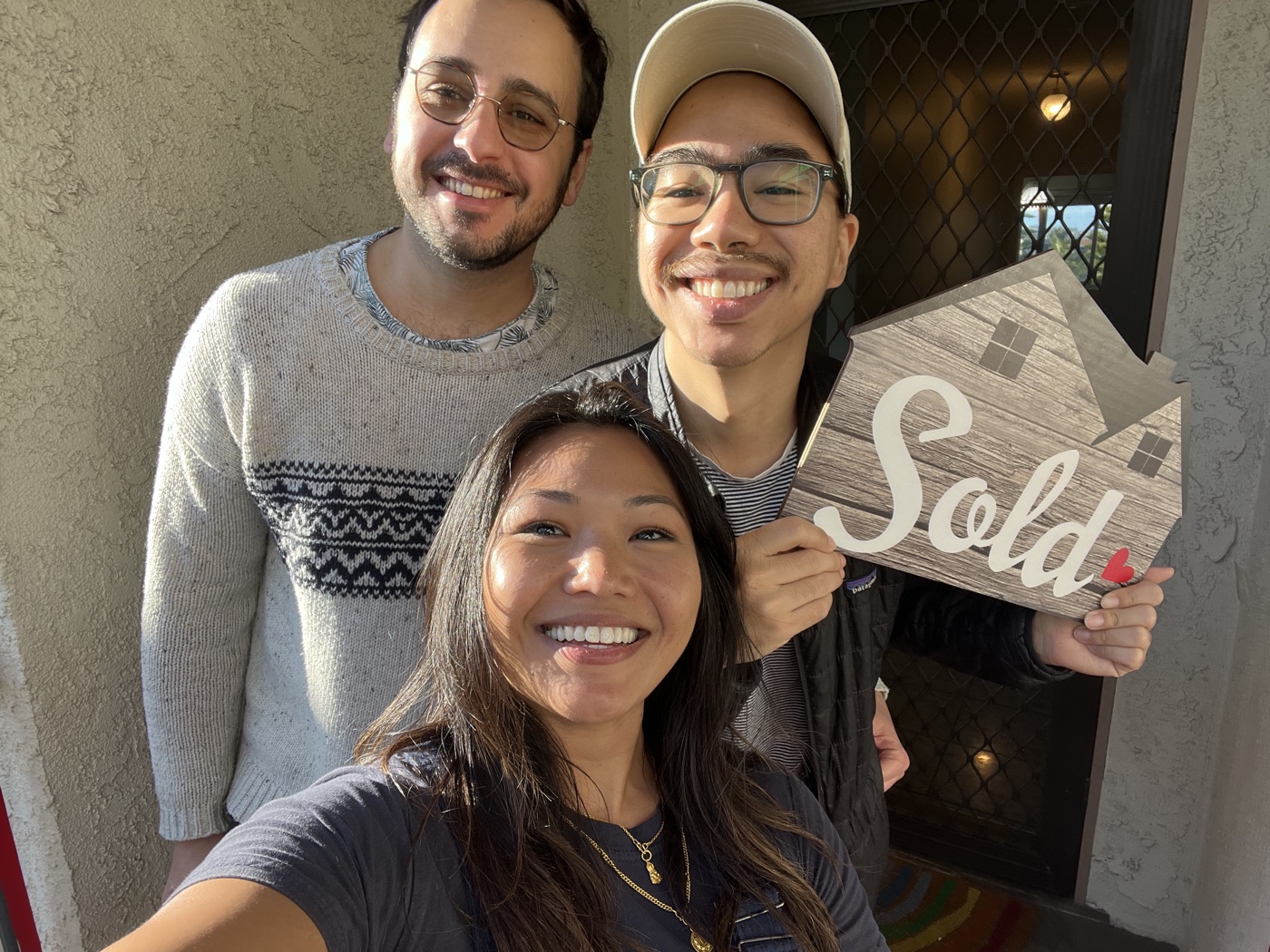 Clients smiling with Dianna and holding a sold sign on closing day