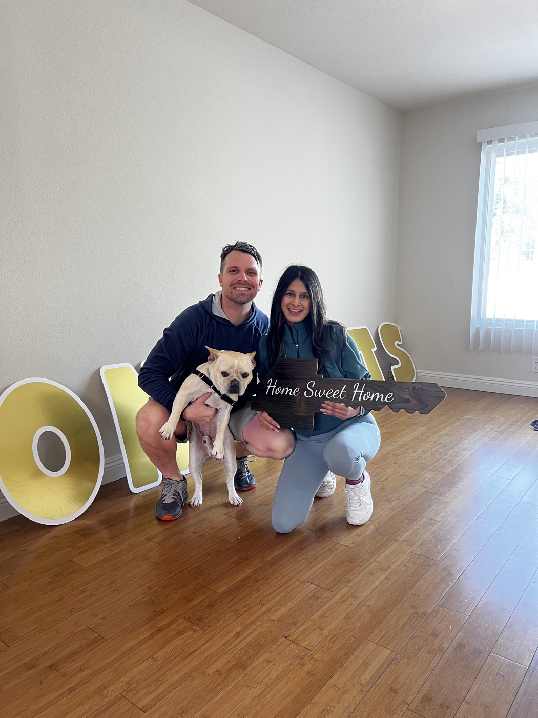 Clients smiling with a Home Sweet Home sign after buying a home